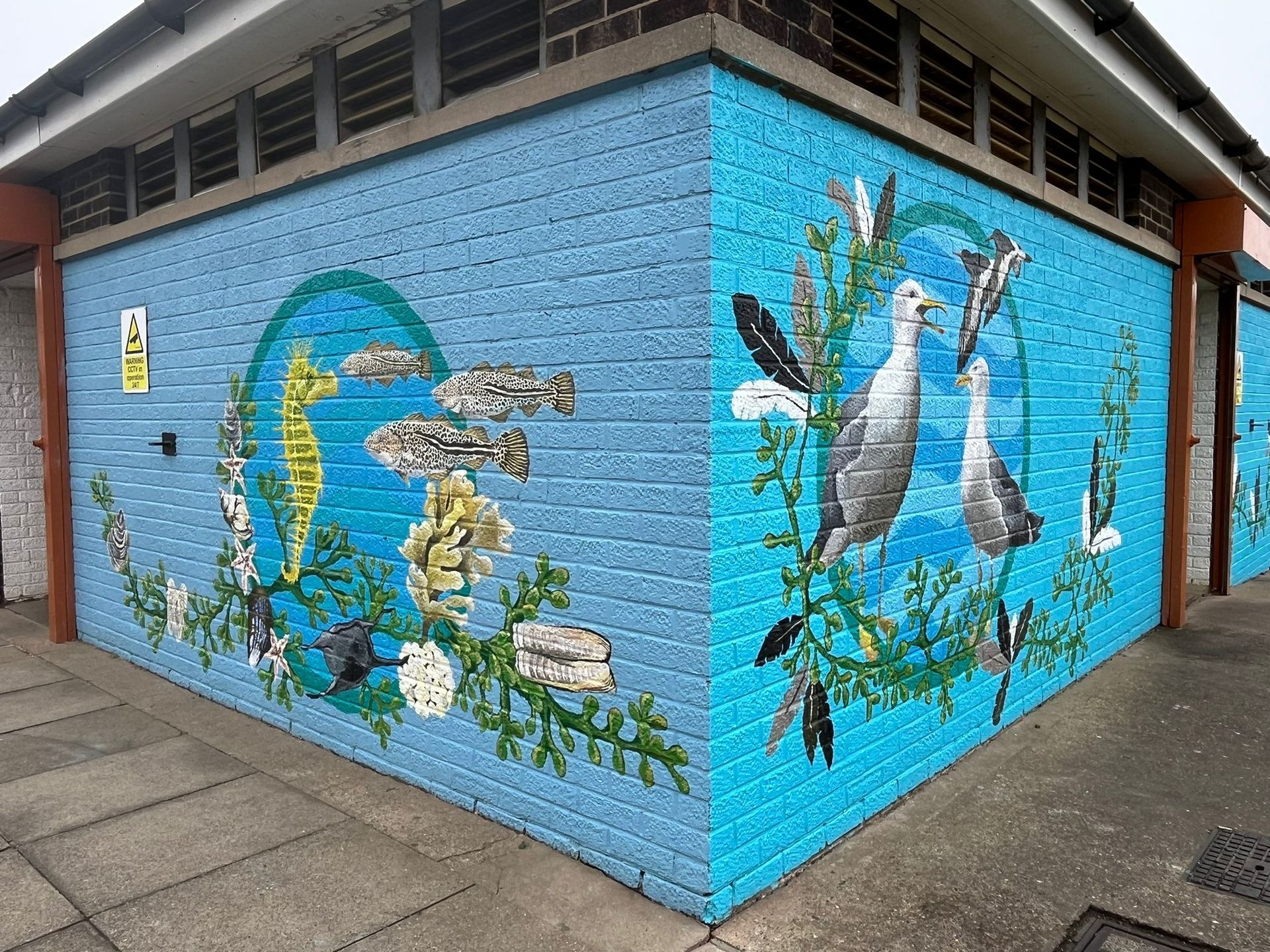 A blue brick building with a mural on the side of it.
