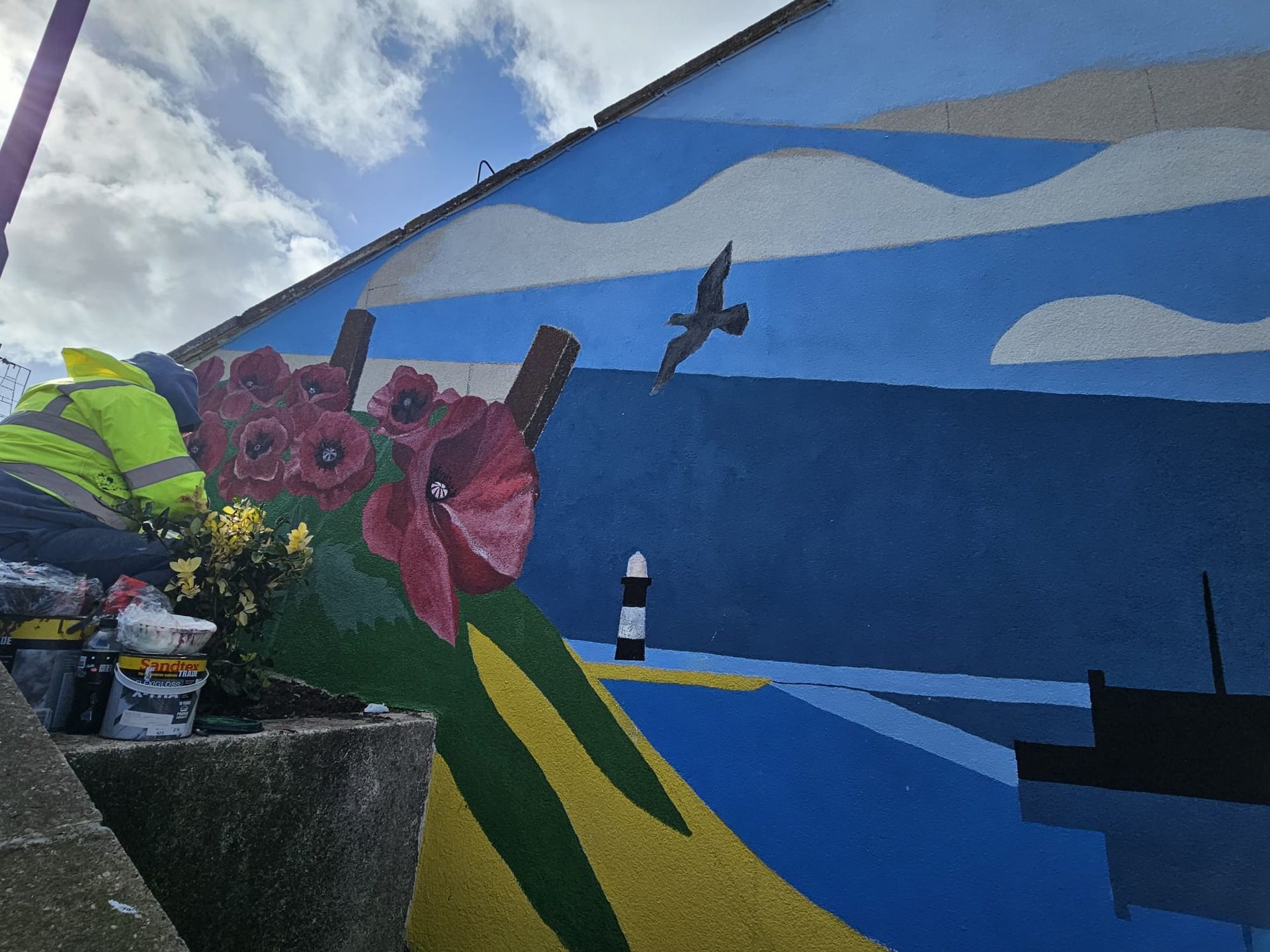A person is painting a mural on the side of a building.