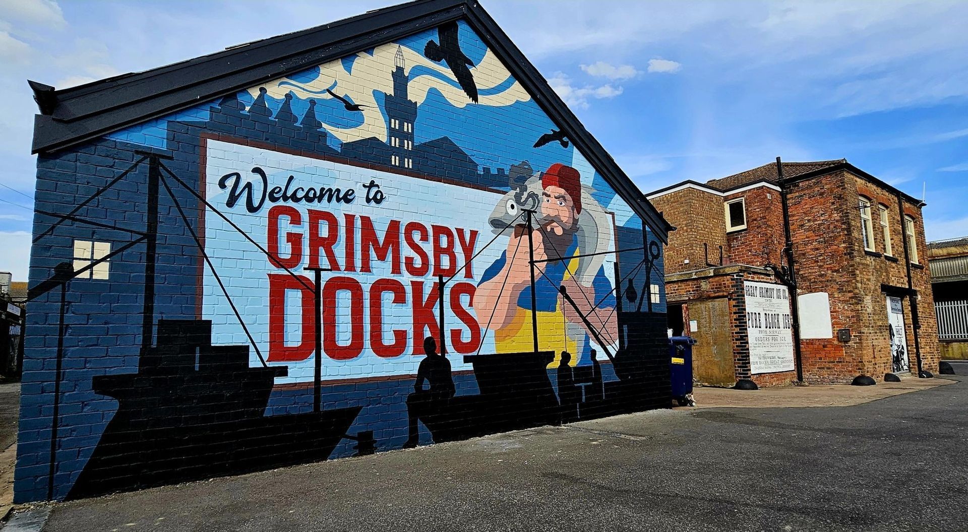 A mural on the side of a building that says welcome to grimsby docks