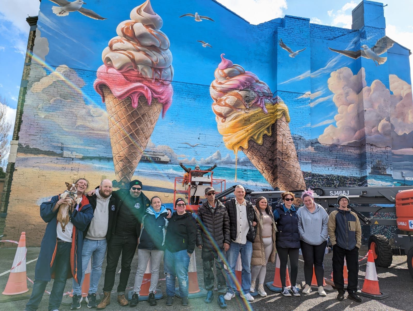 A group of people are standing in front of a mural of ice cream cones.
