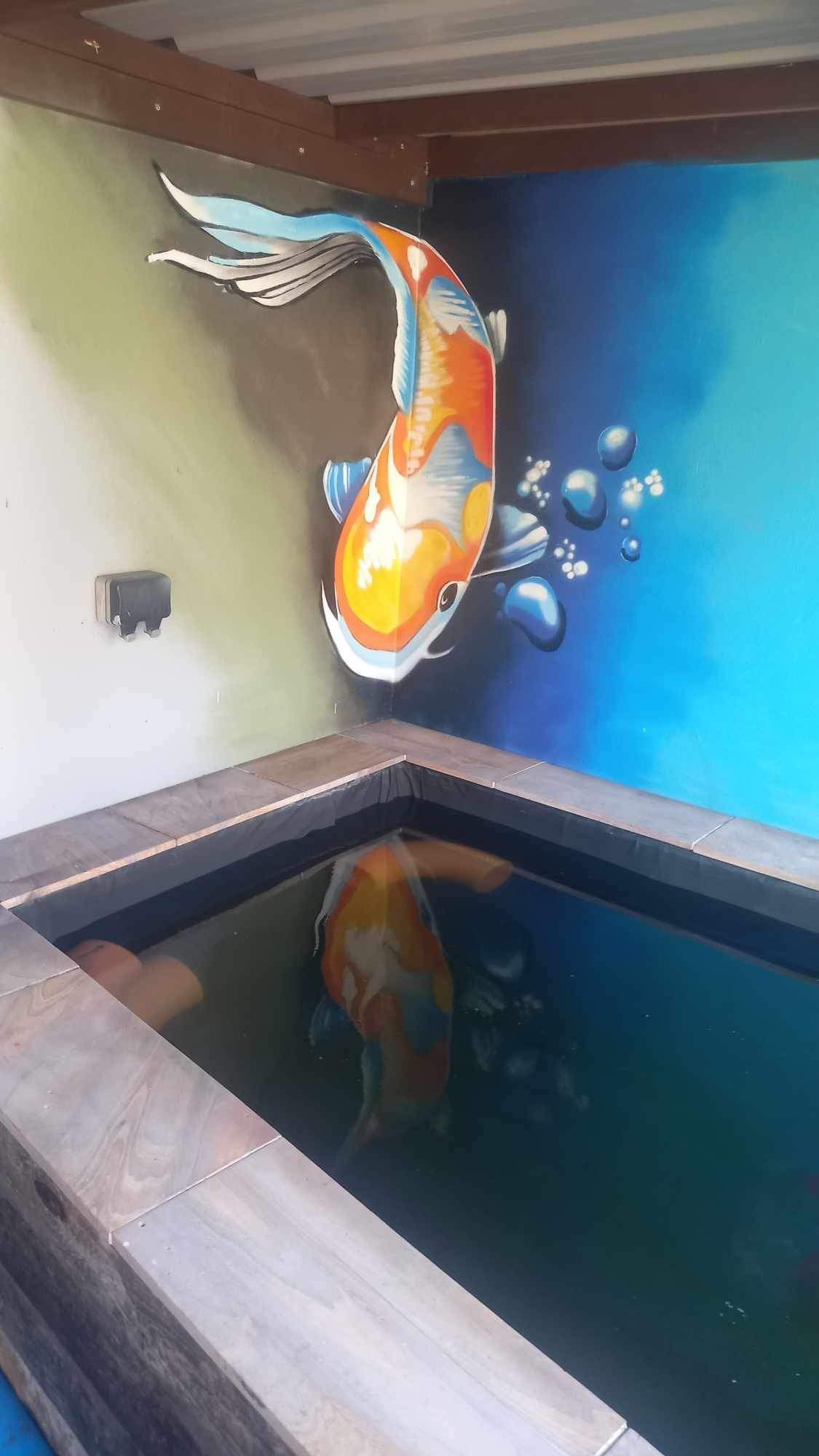 A painting of a fish in a pond on a wall.