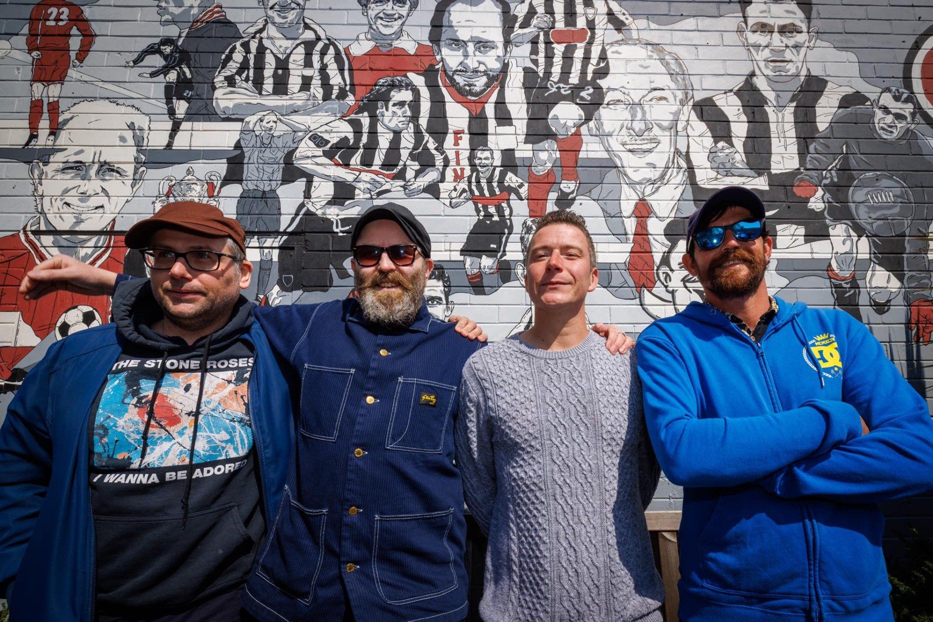 A group of men are posing for a picture in front of a mural.