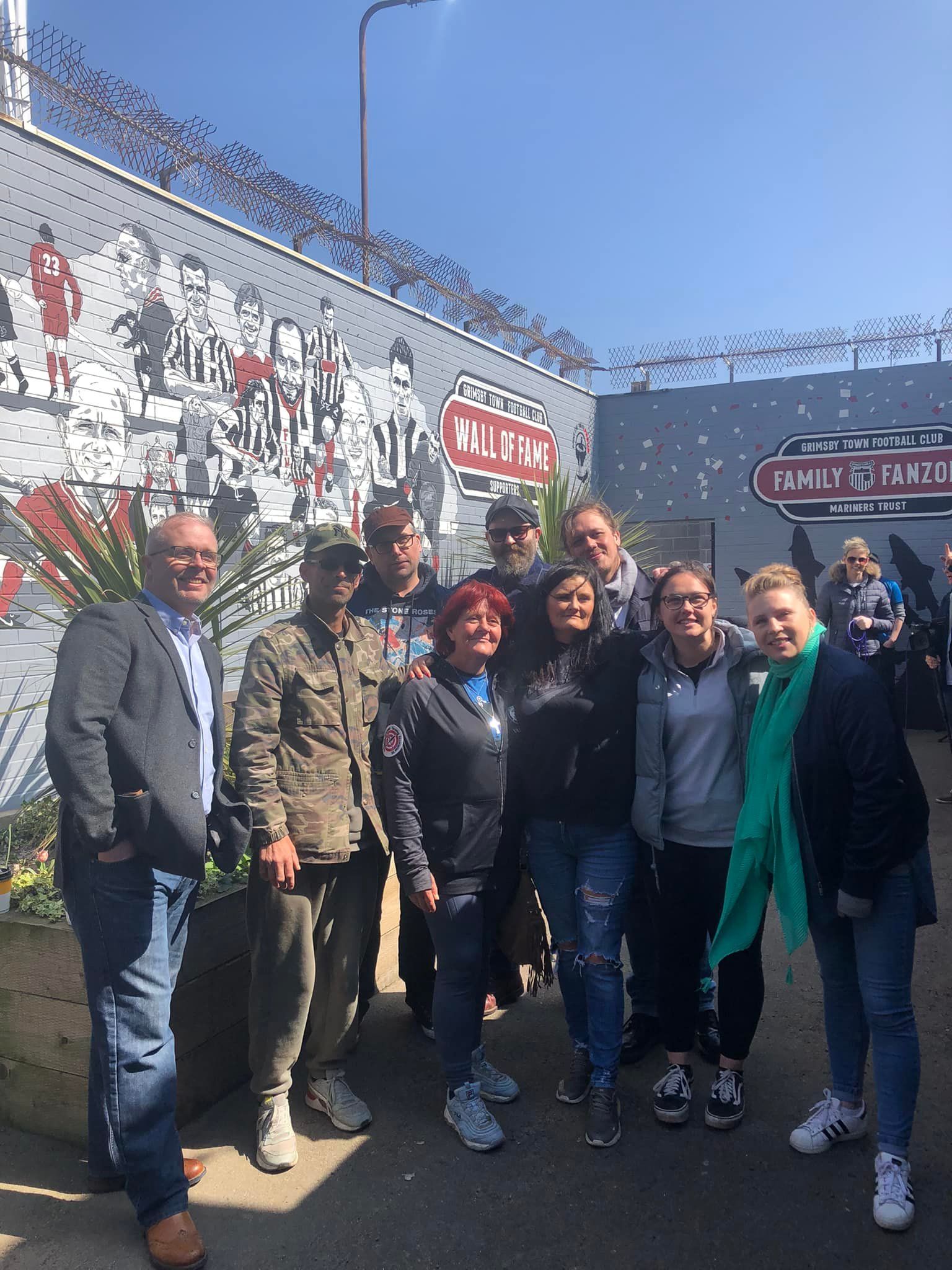 A group of people are posing for a picture in front of a fence.
