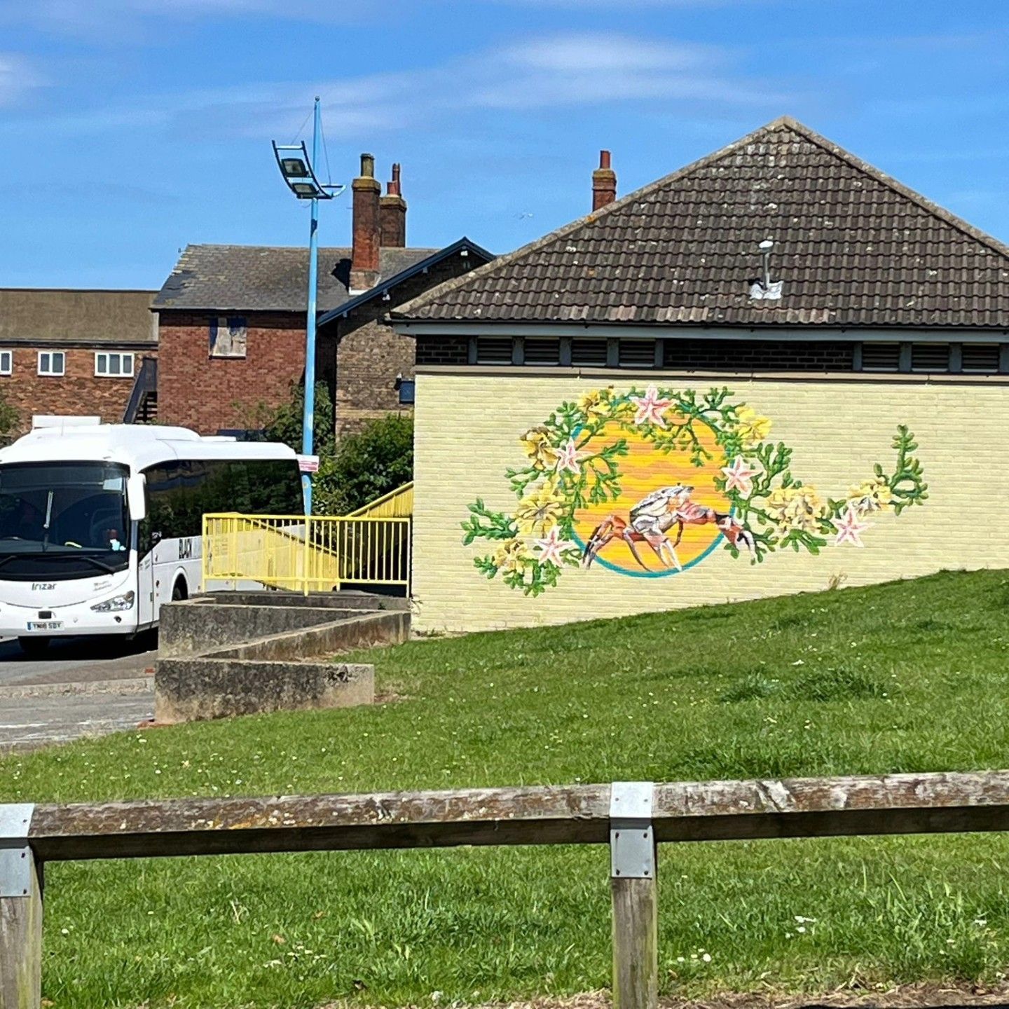 A bus is parked in front of a building with a mural on the side.