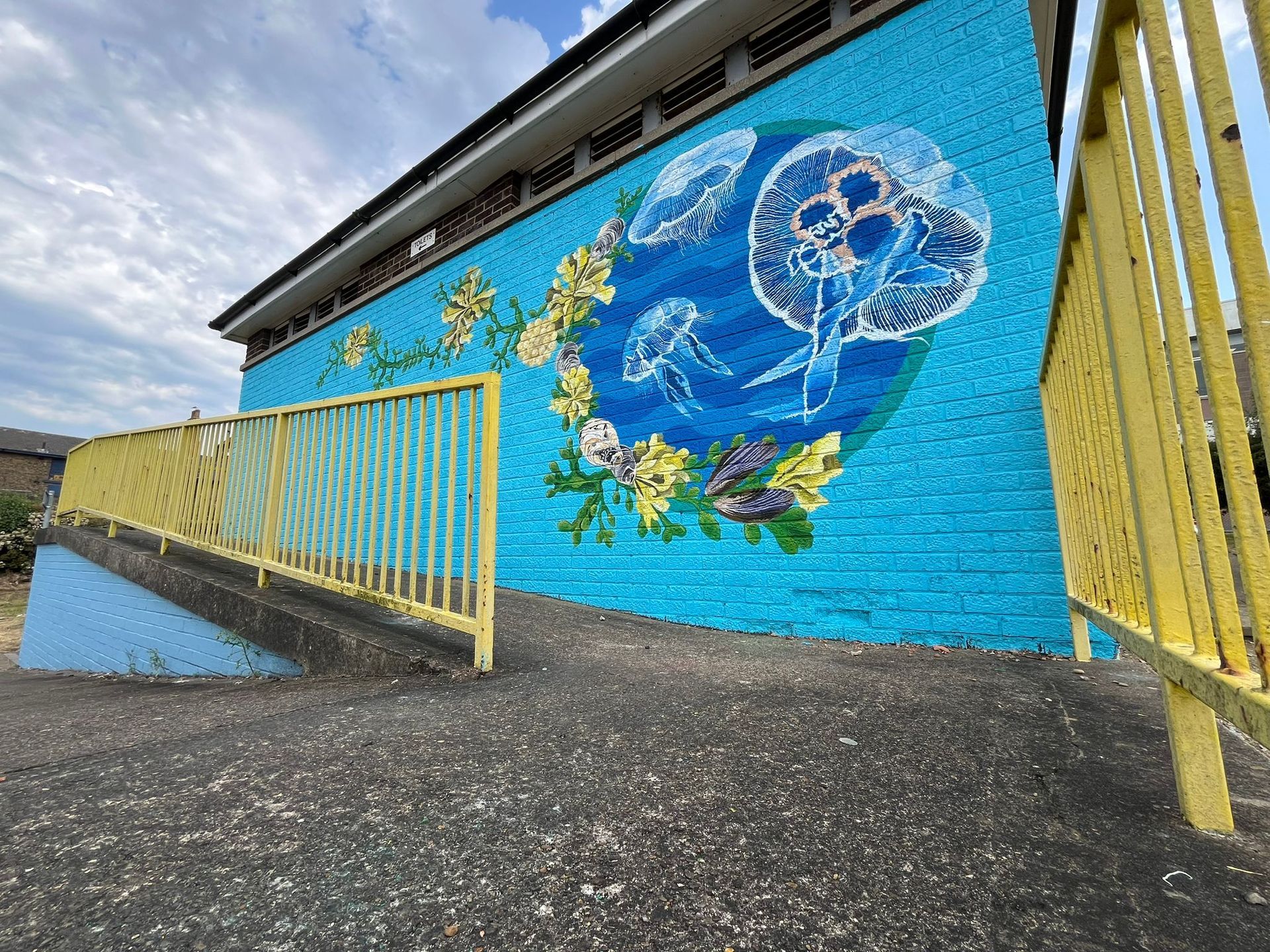 There is a mural on the side of a building with jellyfish and flowers.