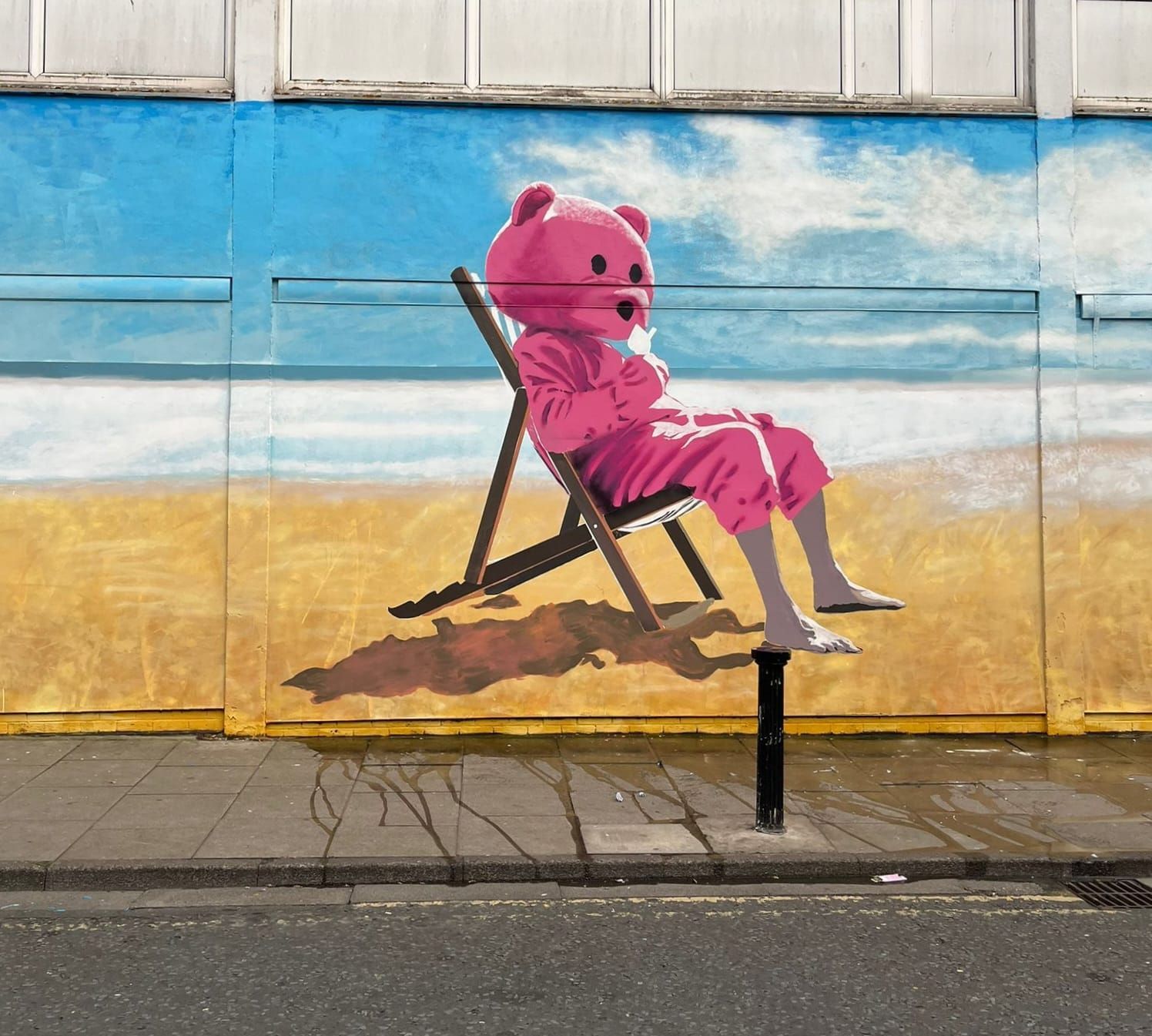 A pink teddy bear is sitting in a beach chair