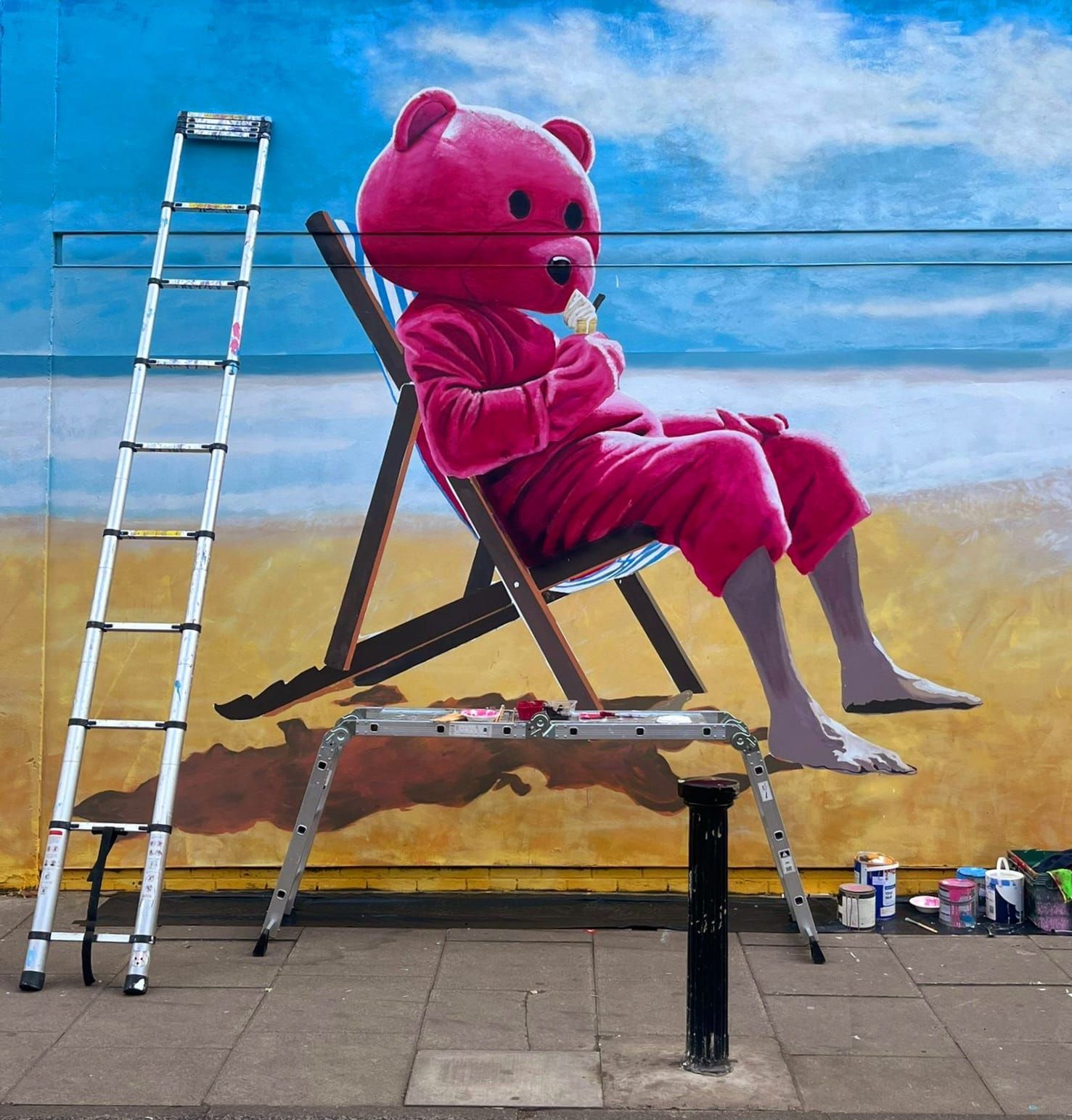 A pink teddy bear is sitting in a beach chair