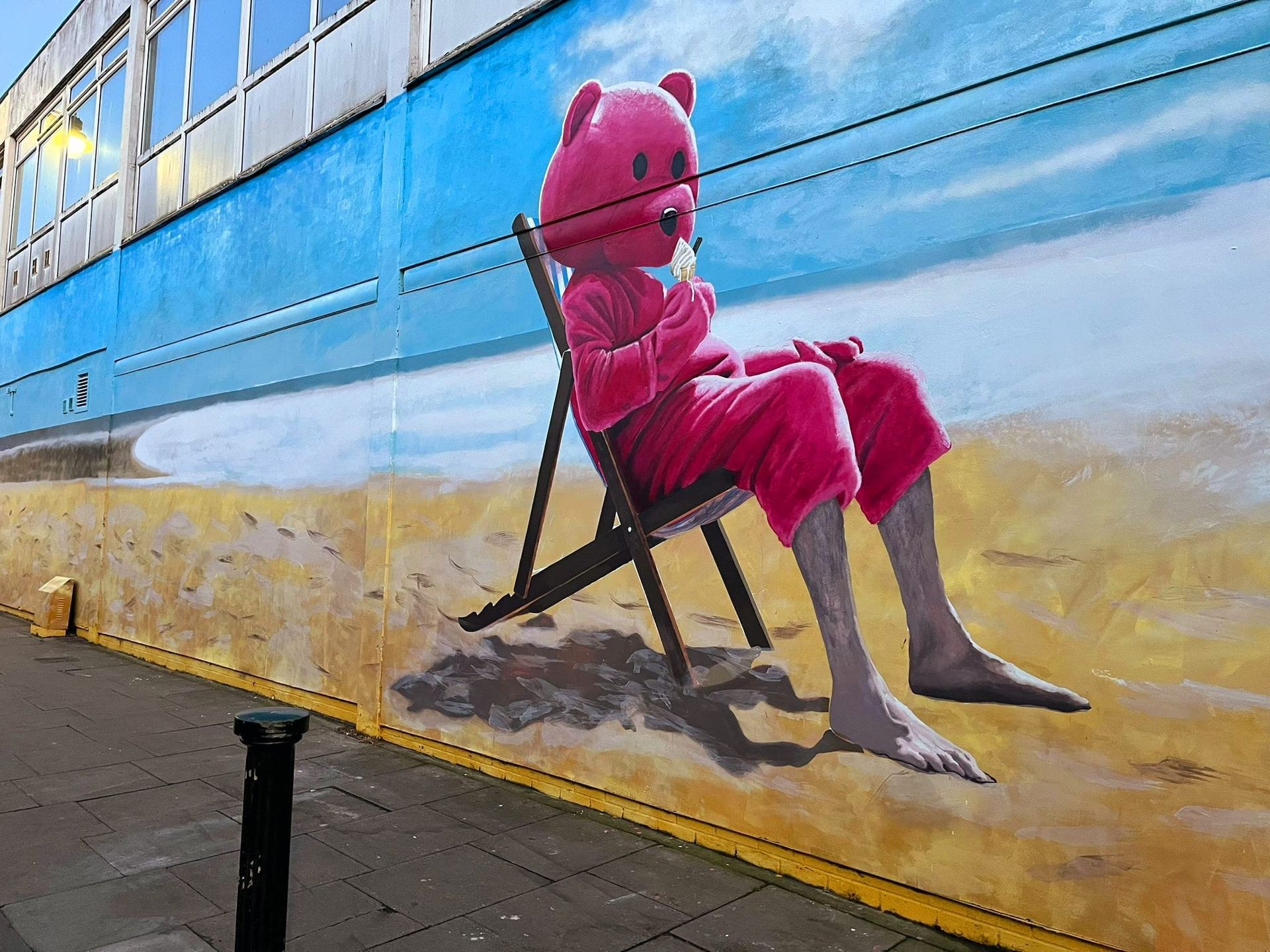 A painting of a pink teddy bear sitting on a beach chair