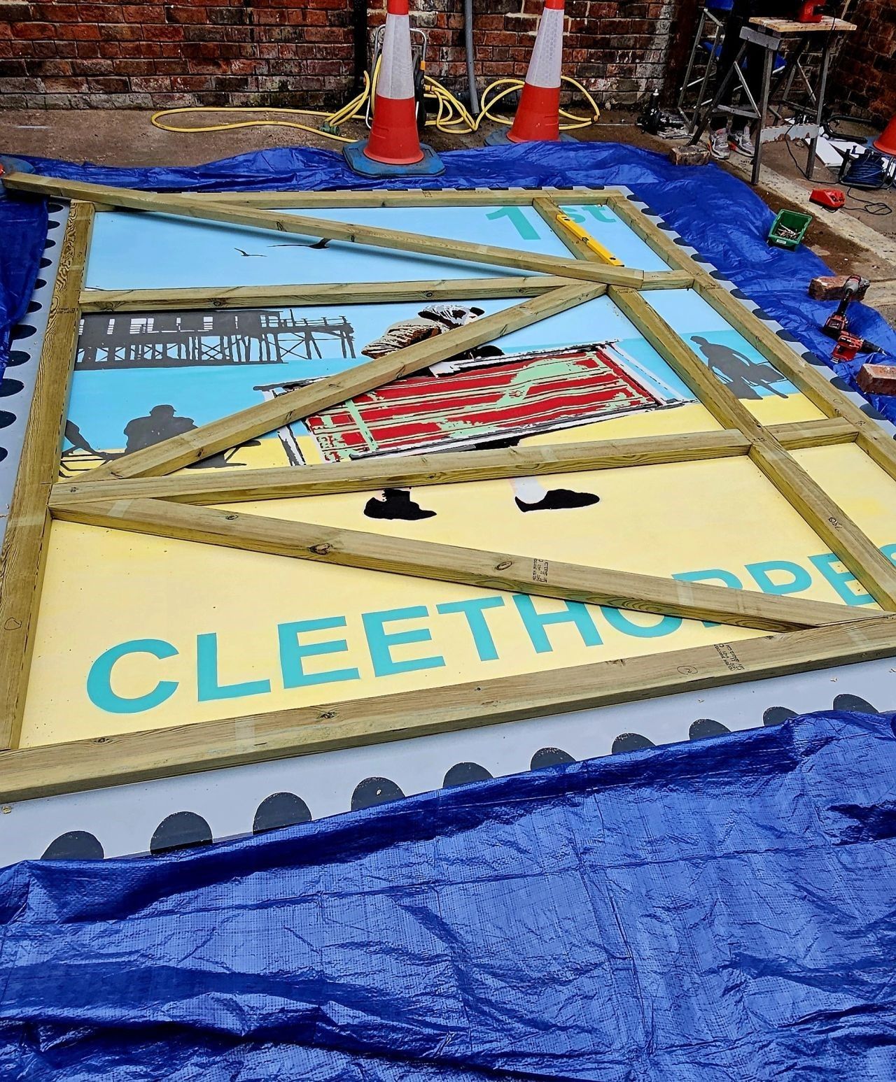 A large piece of art is sitting on top of a blue tarp.