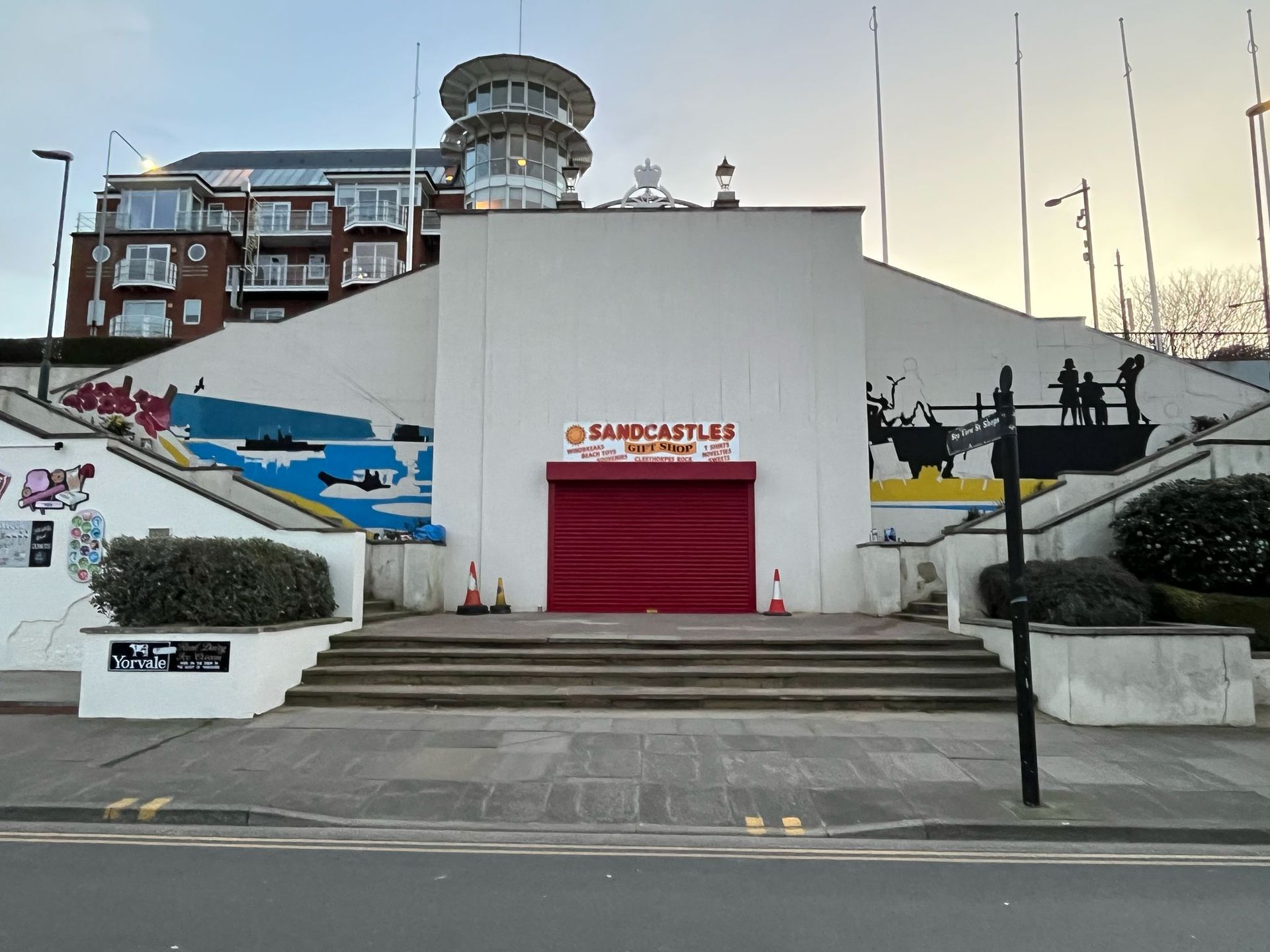 A building with a red garage door and stairs leading up to it
