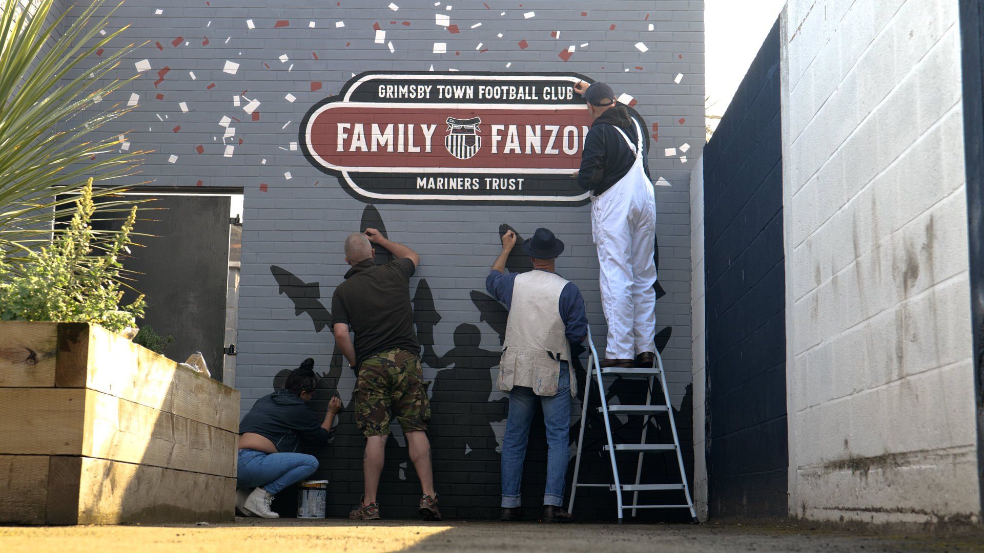 A group of people are painting a sign that says family 's fanzo
