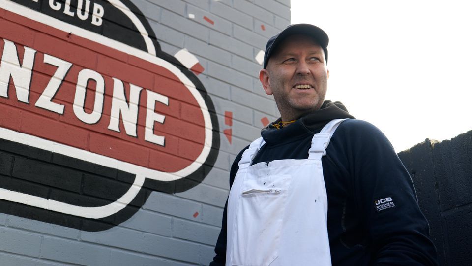 A man is standing in front of a sign that says nzone
