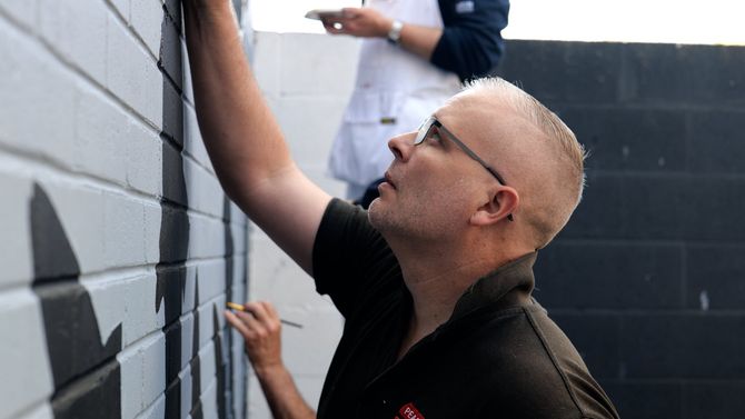 A man is painting a brick wall with a brush.