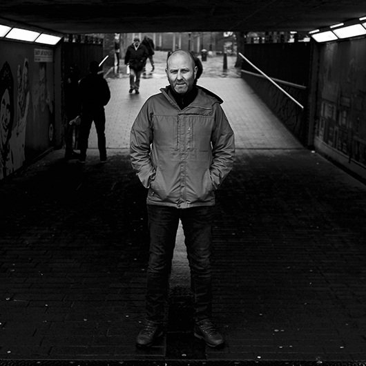 A man is standing in a tunnel with his hands in his pockets.