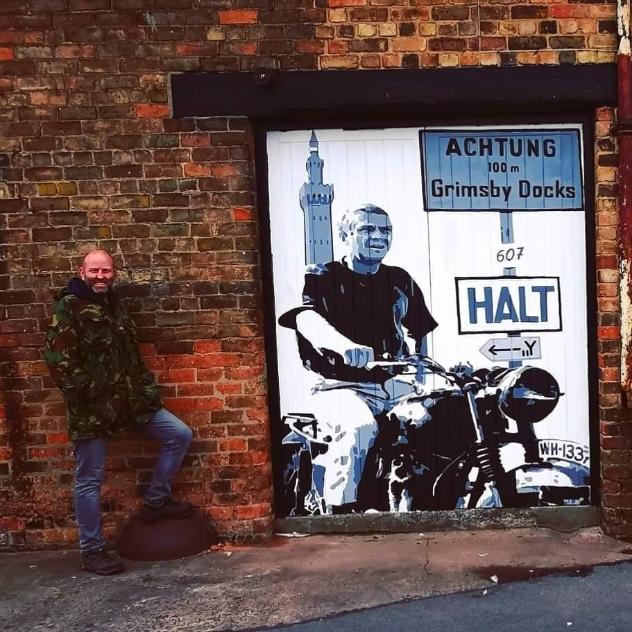 A man stands in front of a mural
