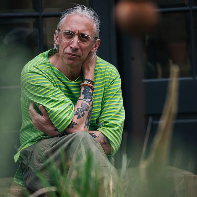 A man wearing a green and yellow striped shirt has a tattoo on his arm
