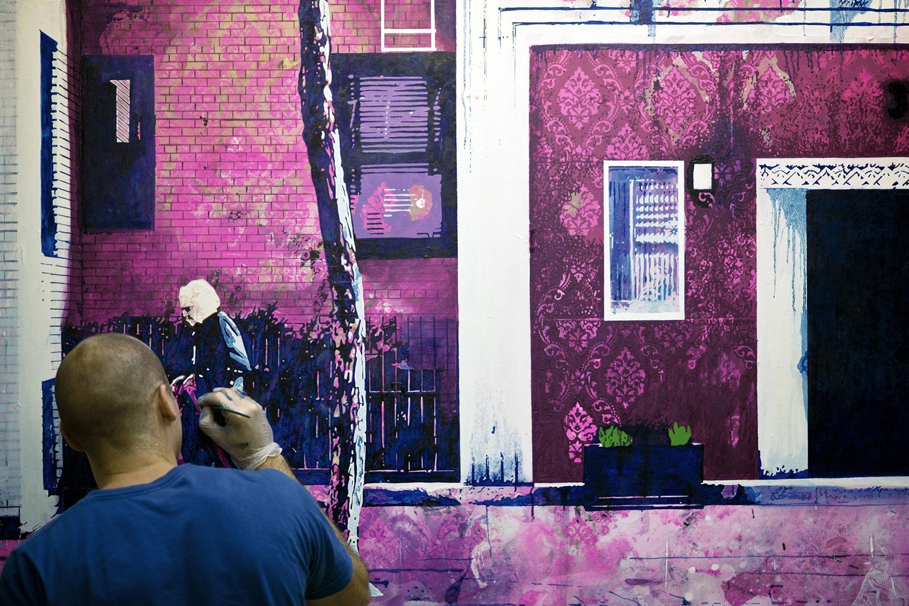 A man in a blue shirt is painting a picture of a building.