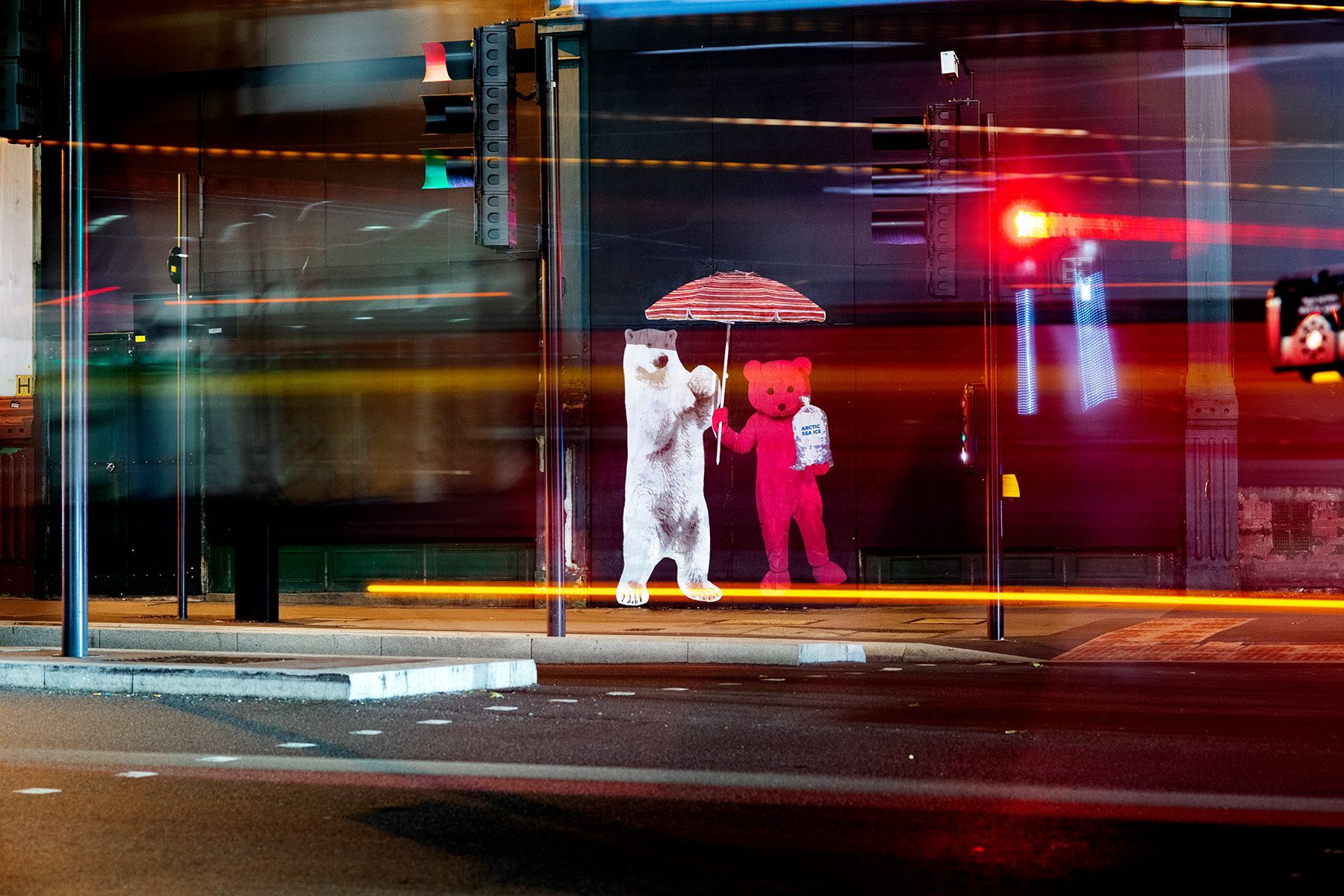 A polar bear and a red teddy bear holding an umbrella