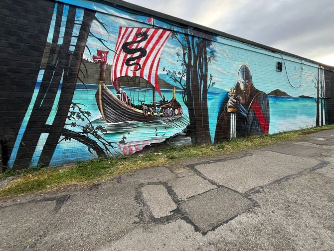 A large mural on the side of a building depicting a viking ship.