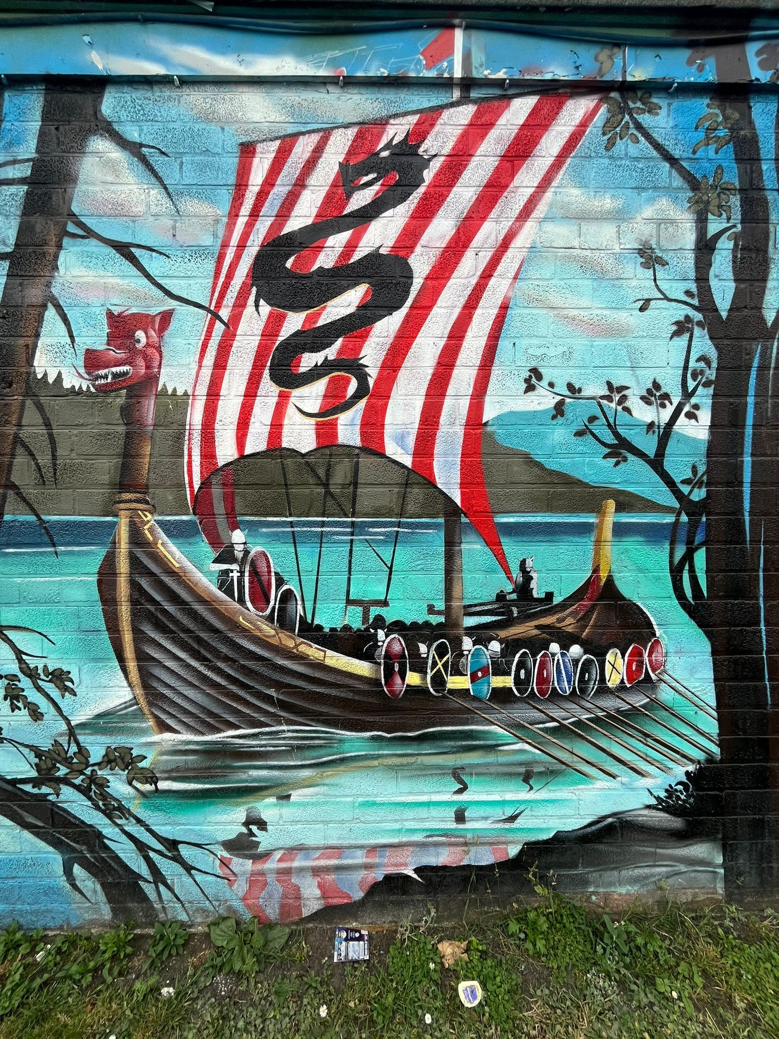 A mural of a viking ship in the water with a dragon on the sail.