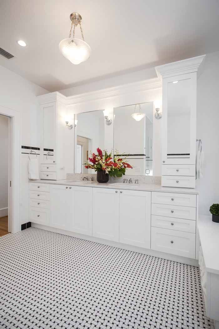 A bathroom with white cabinets and a black and white tile floor.