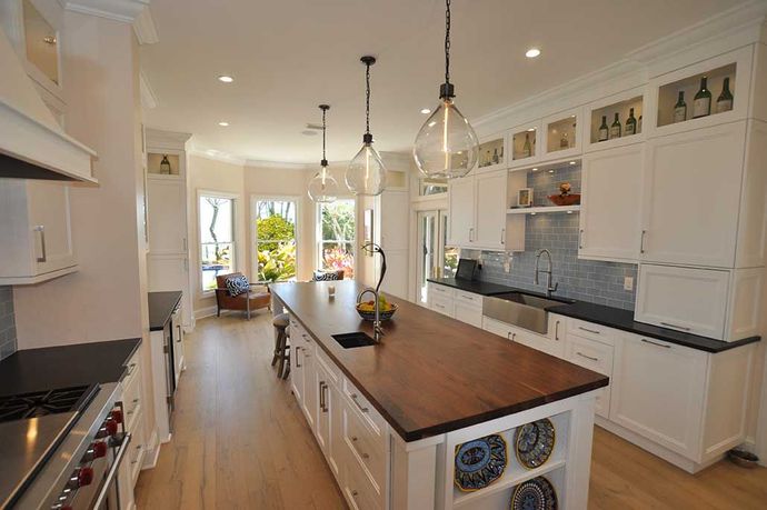 A kitchen with white cabinets and a large island in the middle.