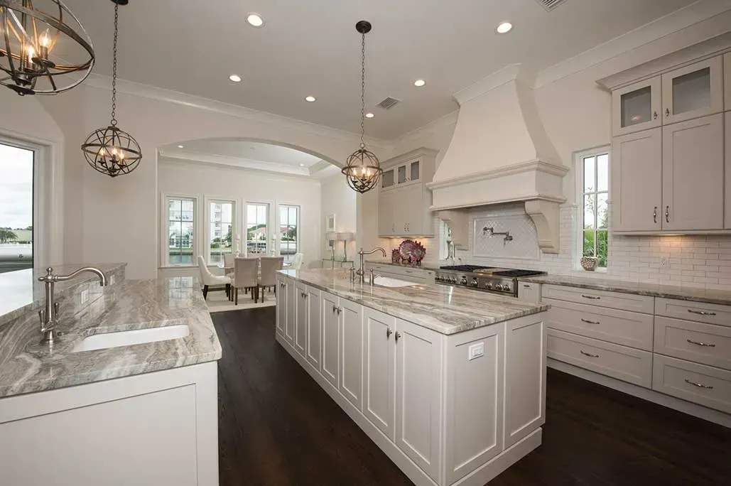 A kitchen with white cabinets , granite counter tops , and a large island.