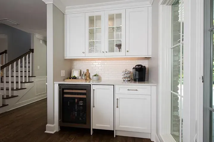 A kitchen with white cabinets and a wine cooler.