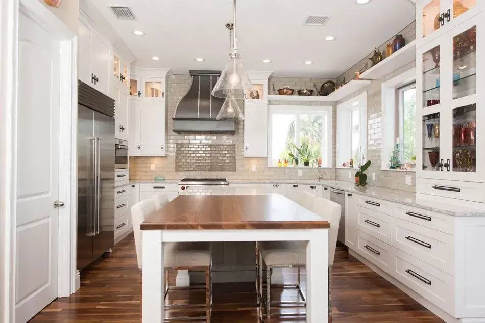 A kitchen with white cabinets and a wooden table