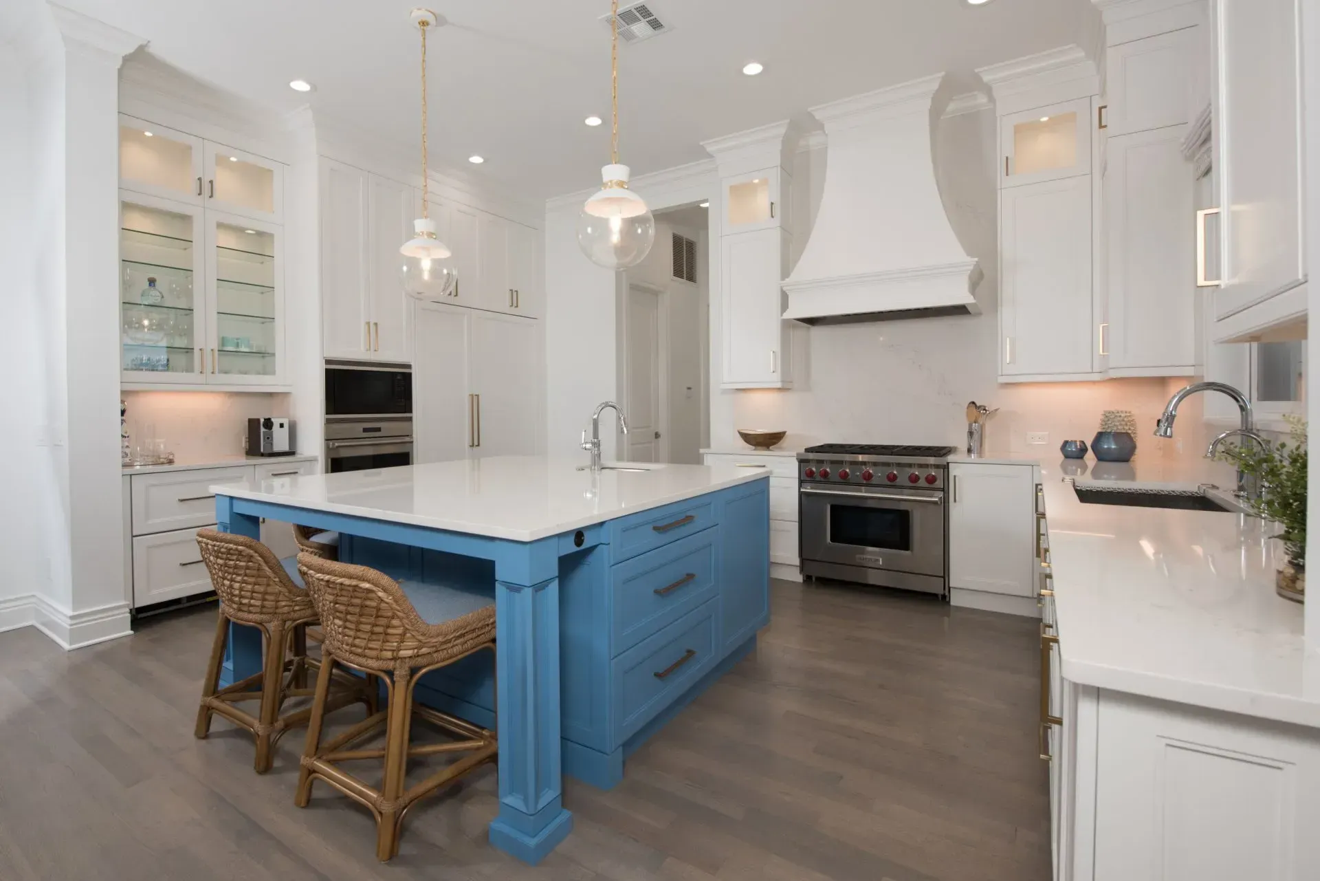 A kitchen with white cabinets and a blue island.