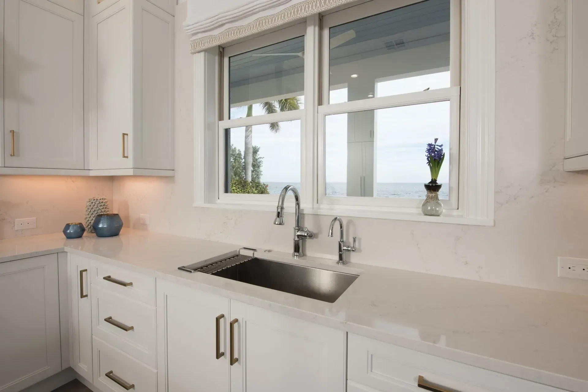 A kitchen with a sink and a window with a view of the ocean.