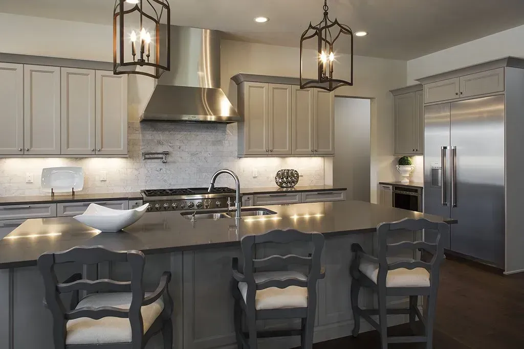 A kitchen with gray cabinets and stainless steel appliances and a large island.
