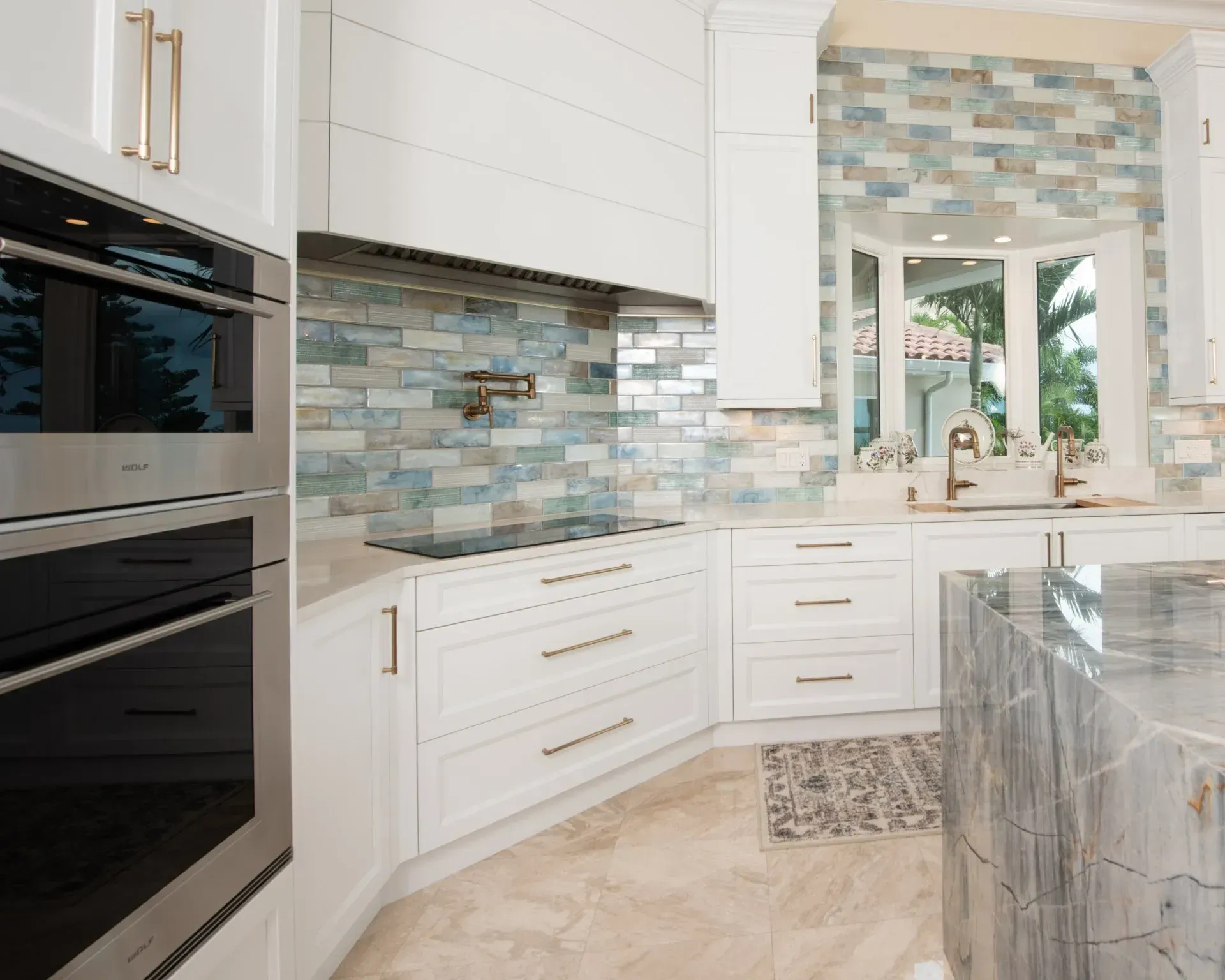 A kitchen with white cabinets , stainless steel appliances , and a large island.