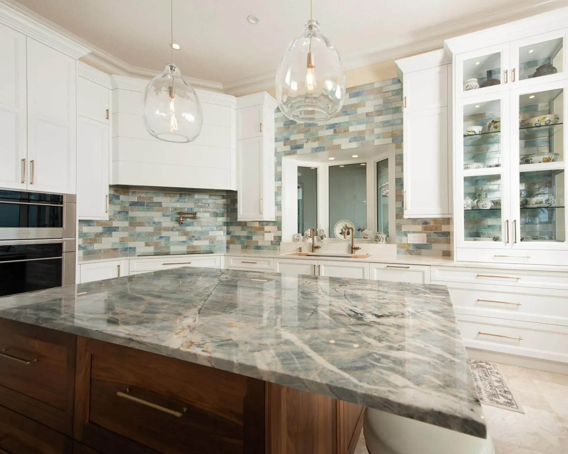 A kitchen with white cabinets and a large granite counter top.