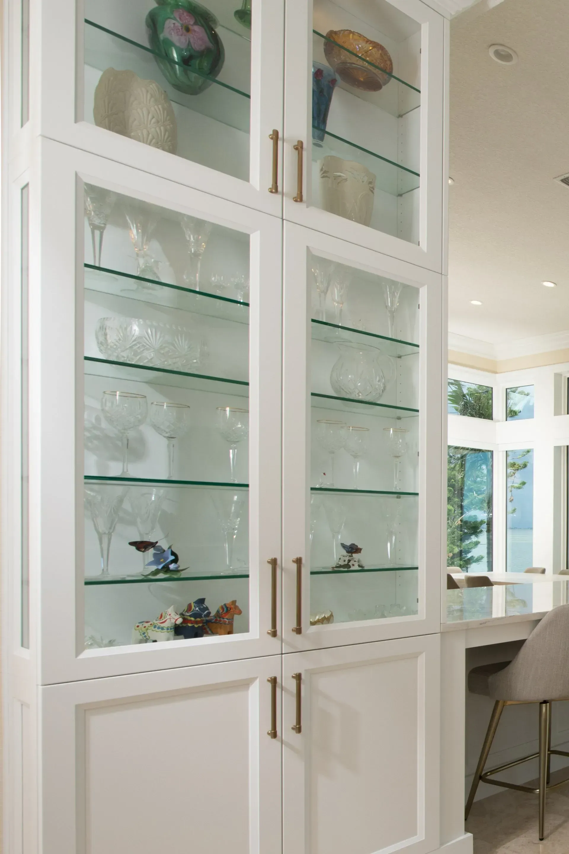 A kitchen with a glass cabinet filled with plates and glasses