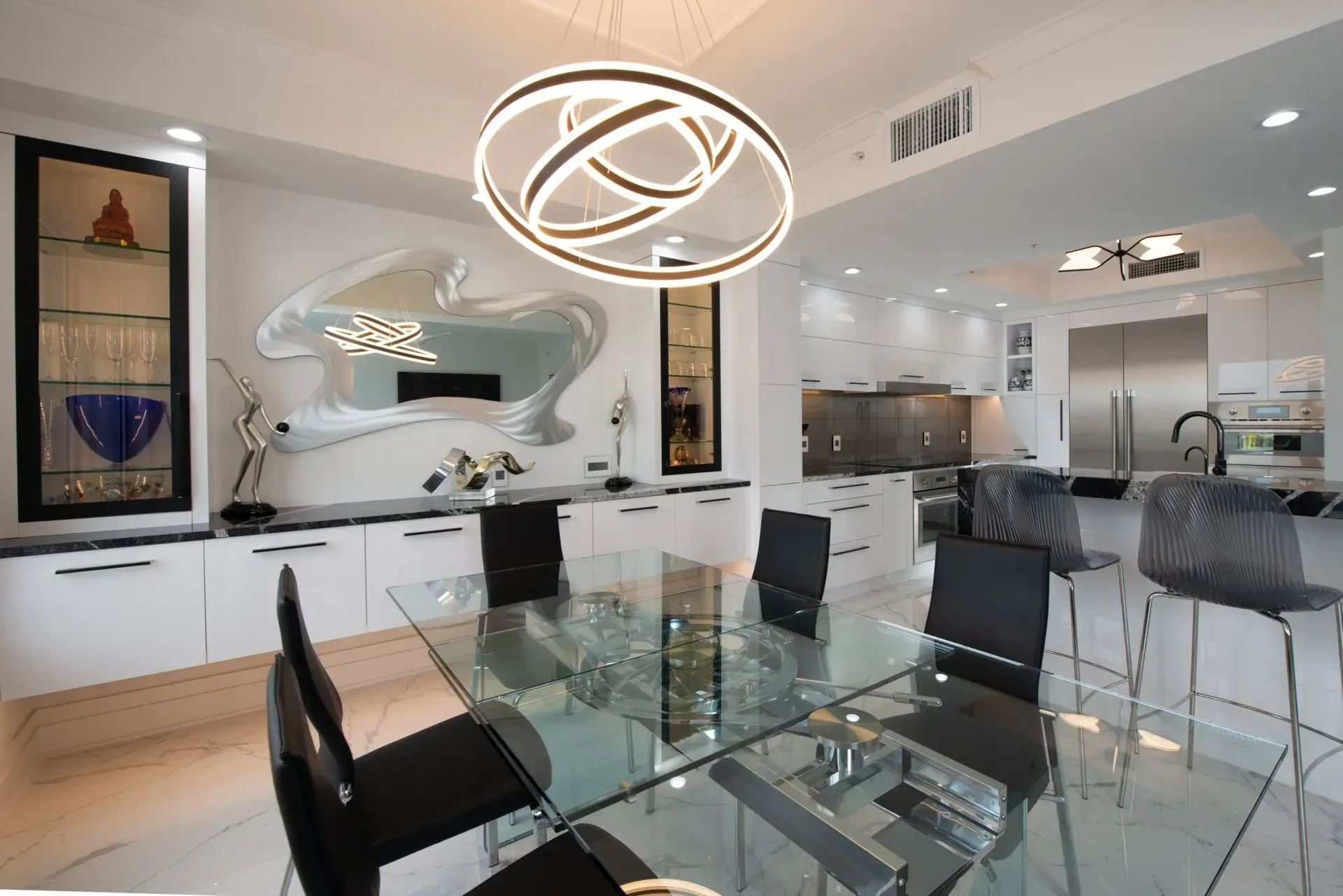 A dining room with a glass table and black chairs