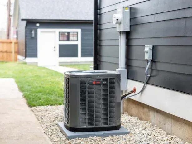 An air conditioner is sitting on the side of a house. An air conditioner is sitting on the side of a house.