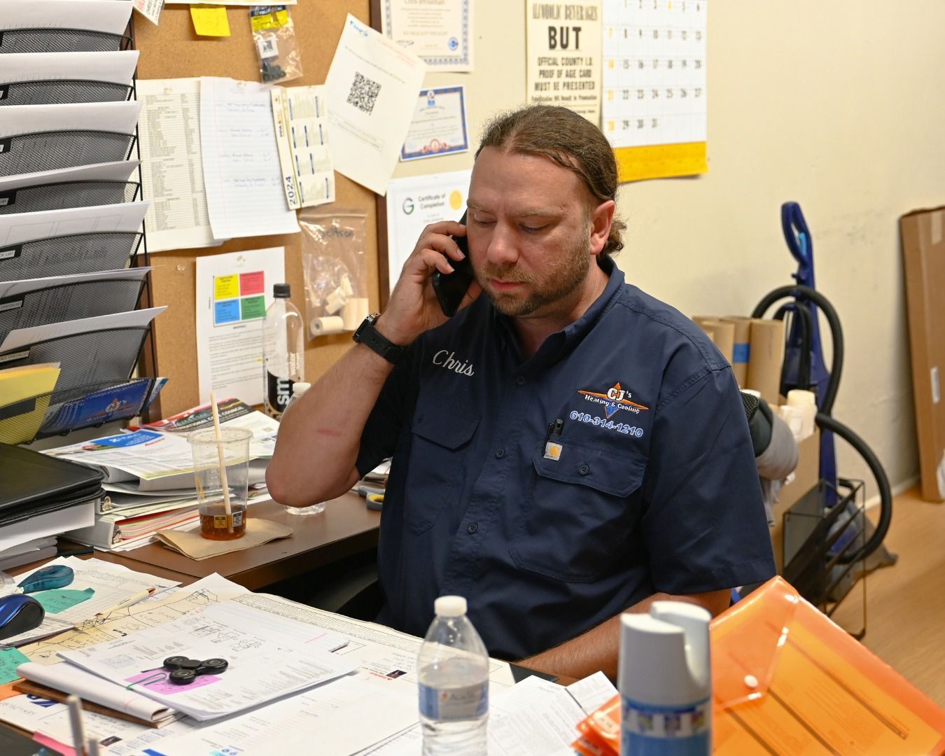 A man is sitting at a desk talking on a cell phone
