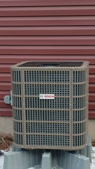 A bosch air conditioner is sitting outside of a house.