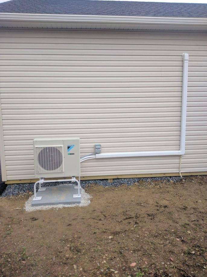 A white air conditioner is installed on the side of a house.