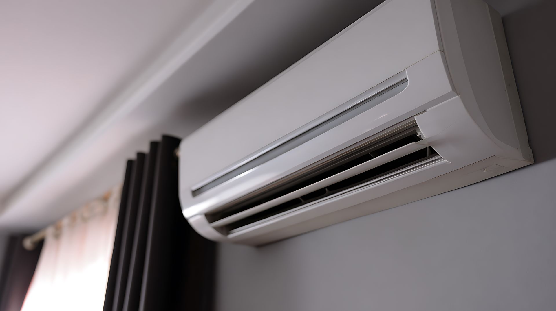 Wall-mounted white air conditioner above a window with curtains