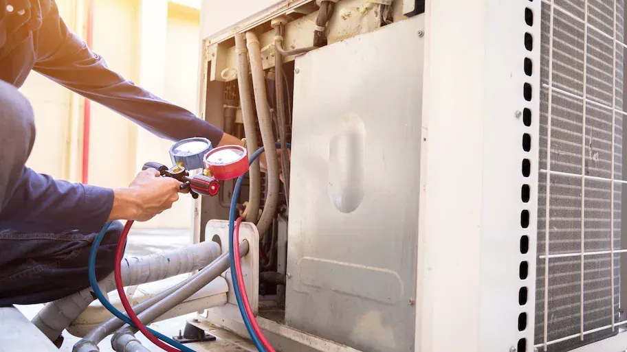 Photo of an HVAC technician working on a heating system. Photo of an HVAC technician working on a heating system.