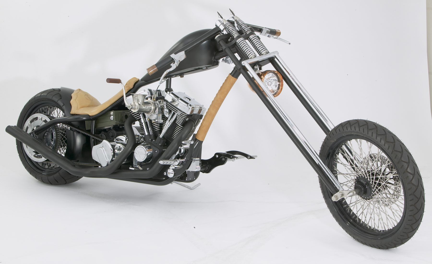 A black chopper motorcycle is sitting on a white surface.
