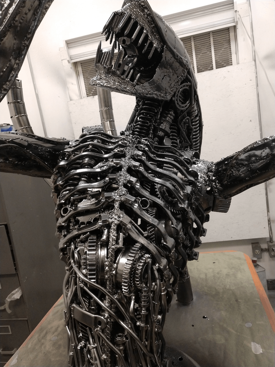 A statue of an alien made out of metal is sitting on a table.