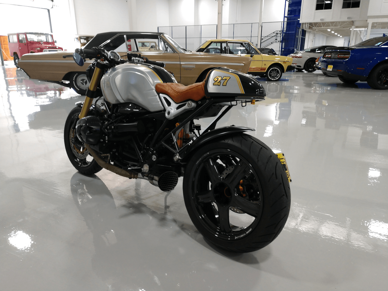 A motorcycle is parked in a garage with cars in the background
