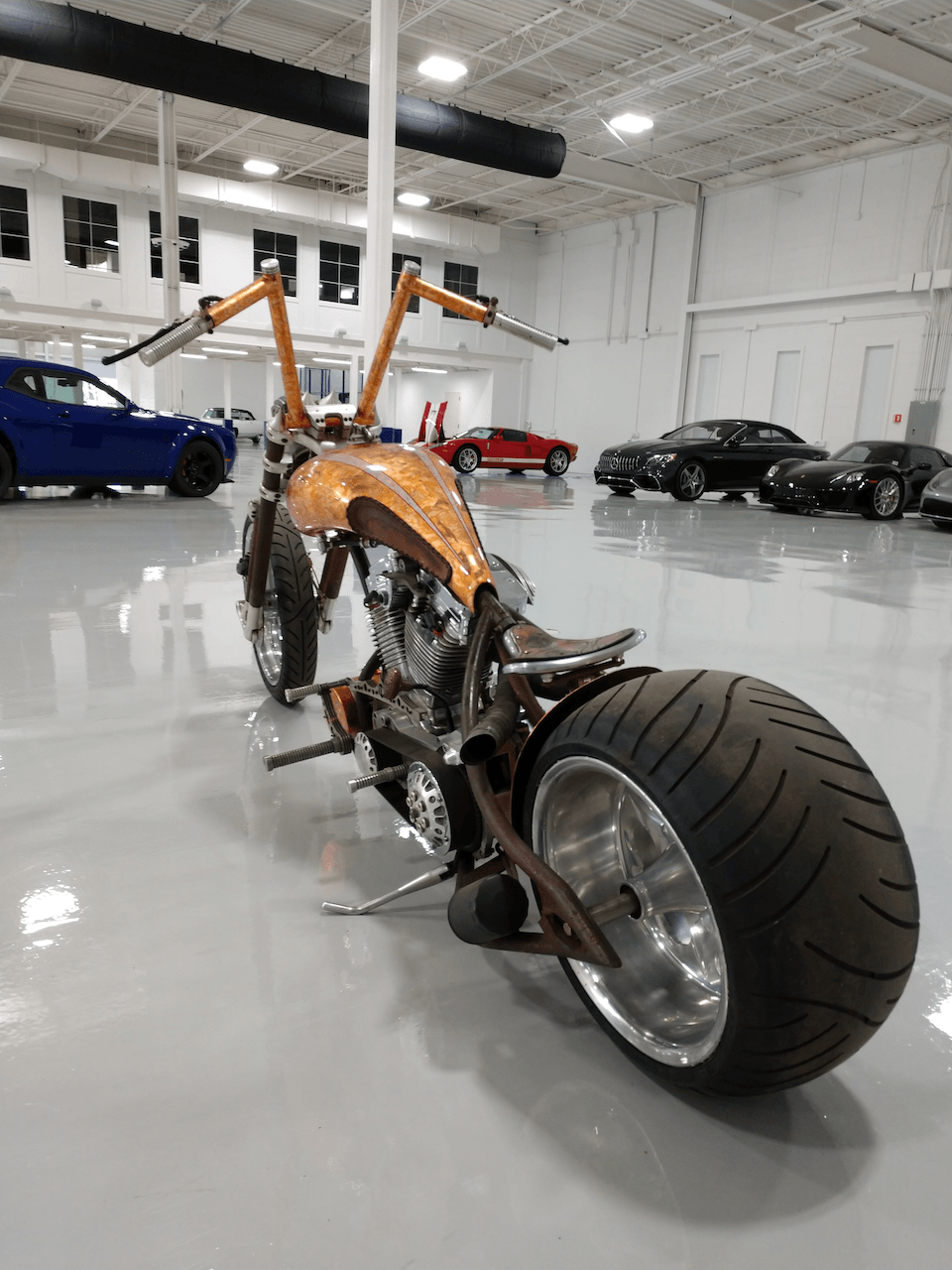 A motorcycle is parked in a garage with cars parked behind it