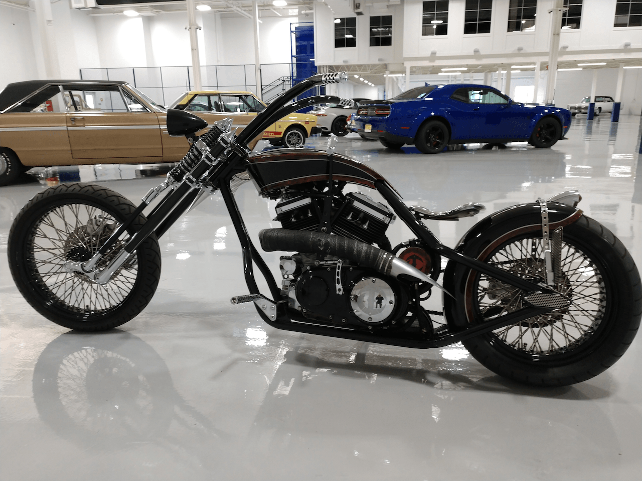 A motorcycle is parked in a garage next to a blue car.