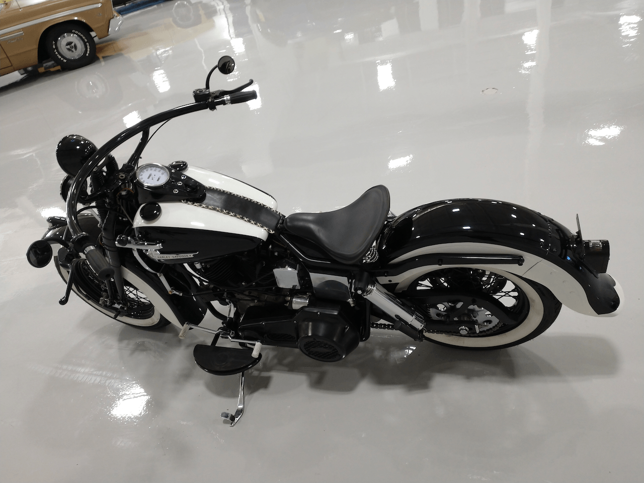 A black and white motorcycle is parked in a garage next to a car.