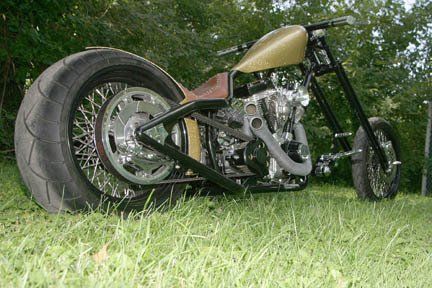 A chopper motorcycle is parked in the grass.