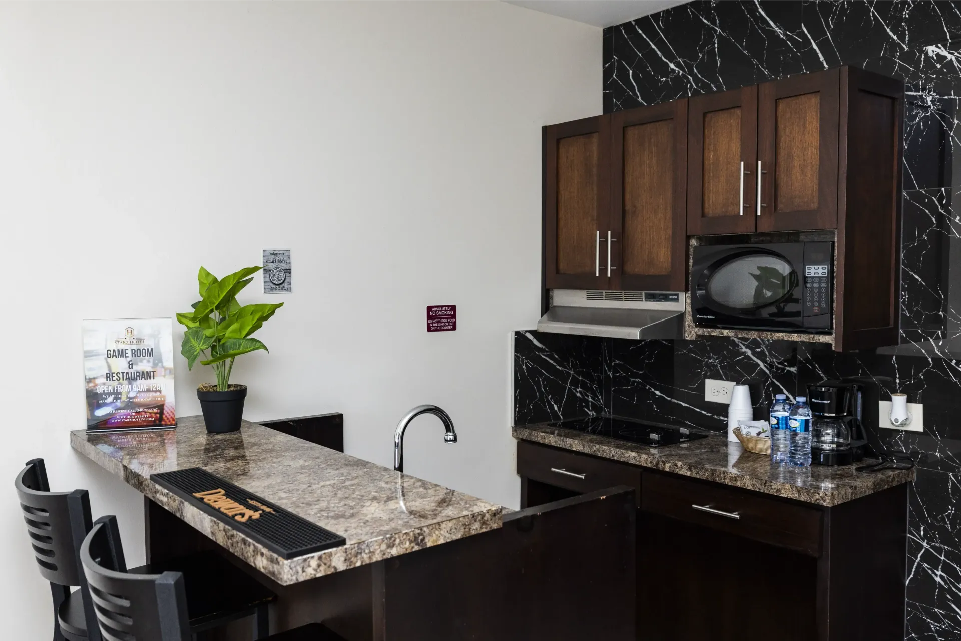 Small kitchen area with cabinets, microwave, and countertop bar.